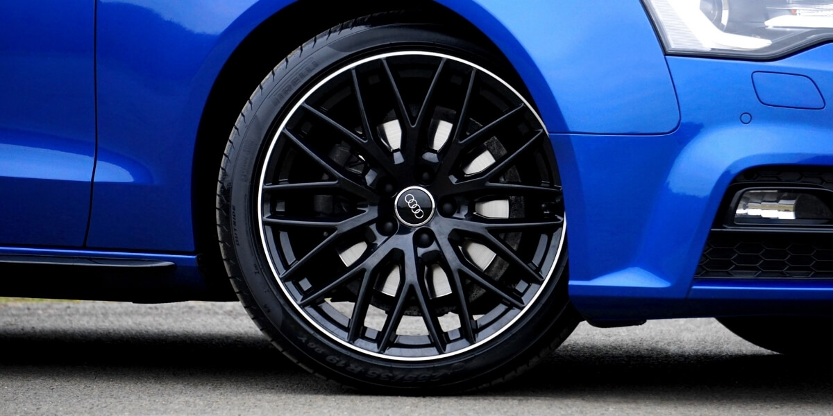 koło z czarną felgą na niebieskim audi